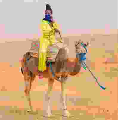 Woman riding on a camel through the Moroccan dessert.