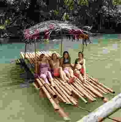 Four girl travellers sitting on a bamboo raft.