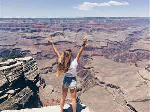 Traveller with hands up looking across the Grand Canyon National Park, United States