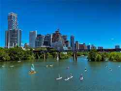 City skyline of Austin, Texas with paddleboarders going under a bridge