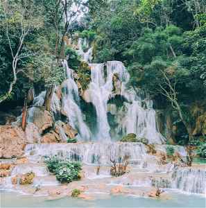 A waterfall surrounded by trees in Luang Prabang, Laos
