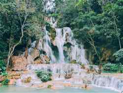 A waterfall surrounded by trees in Luang Prabang, Laos