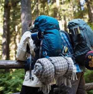 Two people with backpacks in a wooded area
